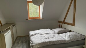 A bedroom with a bed, a desk, and a window.