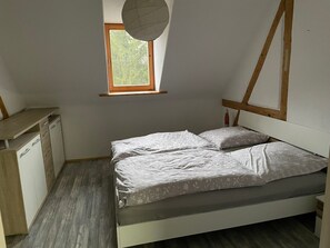 A bedroom with a bed, a desk, and a window.