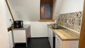 A small kitchen with a window, a coffee maker, a sink, and patterned tiles.
