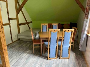 A room with a wooden table and chairs, a sofa, and a green wall.