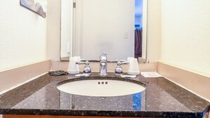 Un baño con lavamanos, dos grifos y dos vasos.