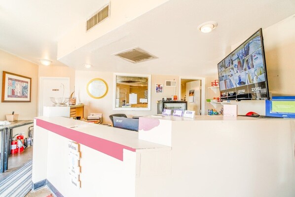 A reception desk with a computer monitor, a fire extinguisher, and a bulletin board.