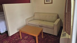 A small room with a sofa, a wooden table, and a framed picture on the wall. - King Bed Accessible Non-Smoking (Chickamauga)