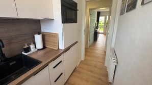 A modern kitchen with a wooden countertop, a built-in microwave, and a view into the adjacent dining area. - Felicitas Maris - Happiness on the Baltic Sea in Dahme! (Dahme)