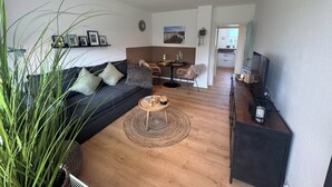 A living room with a sofa, coffee table, and TV stand. There is a dining area with a table and chairs. - Felicitas Maris - Happiness on the Baltic Sea in Dahme! (Dahme)