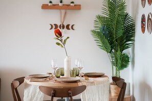 A round dining table with a white tablecloth, surrounded by chairs, and a vase with a red flower centerpiece. - Sahara Oasis - Rooftop Pool, CBD & Sunset Balcony (Darwin City)
