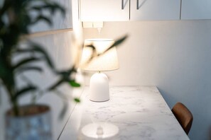 Ein Tisch mit einer weißen Lampe, einem Stuhl und einer Pflanze im Vordergrund.