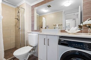 Ein Badezimmer mit Dusche, Toilette, Waschbecken und einer Waschmaschine.