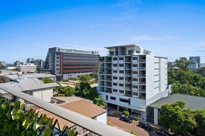 A multi-story building with balconies, a parking area, and surrounding greenery. - Bluewater Retreat | Ocean-Sunset Views, Pool & CBD (Darwin City)
