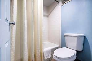 Un baño con inodoro blanco, bañera y cortina de ducha.