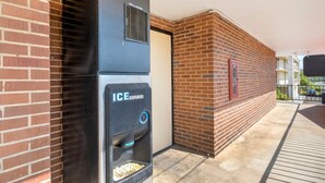 Un espace extérieur avec un mur en briques, un distributeur de glaçons noir et une porte.
