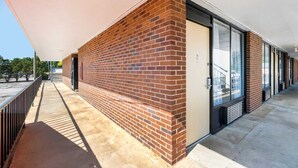 Un bâtiment à la façade en briques, doté de grandes fenêtres et d’une allée couverte.
