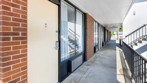 Un couloir avec un mur en briques, une porte en verre dotée d’une fenêtre et un panneau indiquant la sortie.