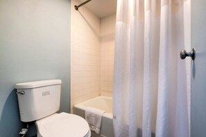 Un baño con inodoro, bañera y cortina de ducha.