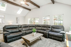 A spacious living room with a large sectional sofa, a wooden coffee table, and a ceiling fan.