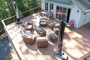 A wooden deck with outdoor furniture, including a sofa, chairs, and a table.