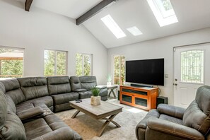A living room with a sectional sofa, a coffee table, a television, and a door with a window.