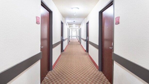 Ein Hotelkorridor mit Türen, auf denen 'Texas' steht und die Nummer 211 tragen.