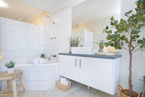 A modern bathroom with a white tiled wall, a large mirror, a sink, and a shower. - Snowy Love - CBD, Parking & Cozy (Darwin City)