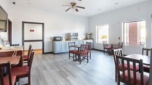 A spacious room with a kitchen area, dining tables, and chairs. - Townhouse Clute Lake Jackson|King Bed (Clute TX)