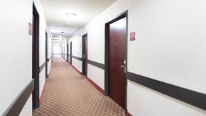 A hotel hallway with doors, carpeted floors, and a ceiling light. - Townhouse Clute Lake Jackson|King Bed (Clute TX)