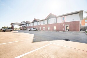 A multi-story building with a parking lot, a covered entrance, and a brick facade.