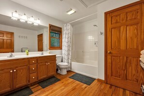 Un baño con tocador de madera, inodoro, ducha y bañera.