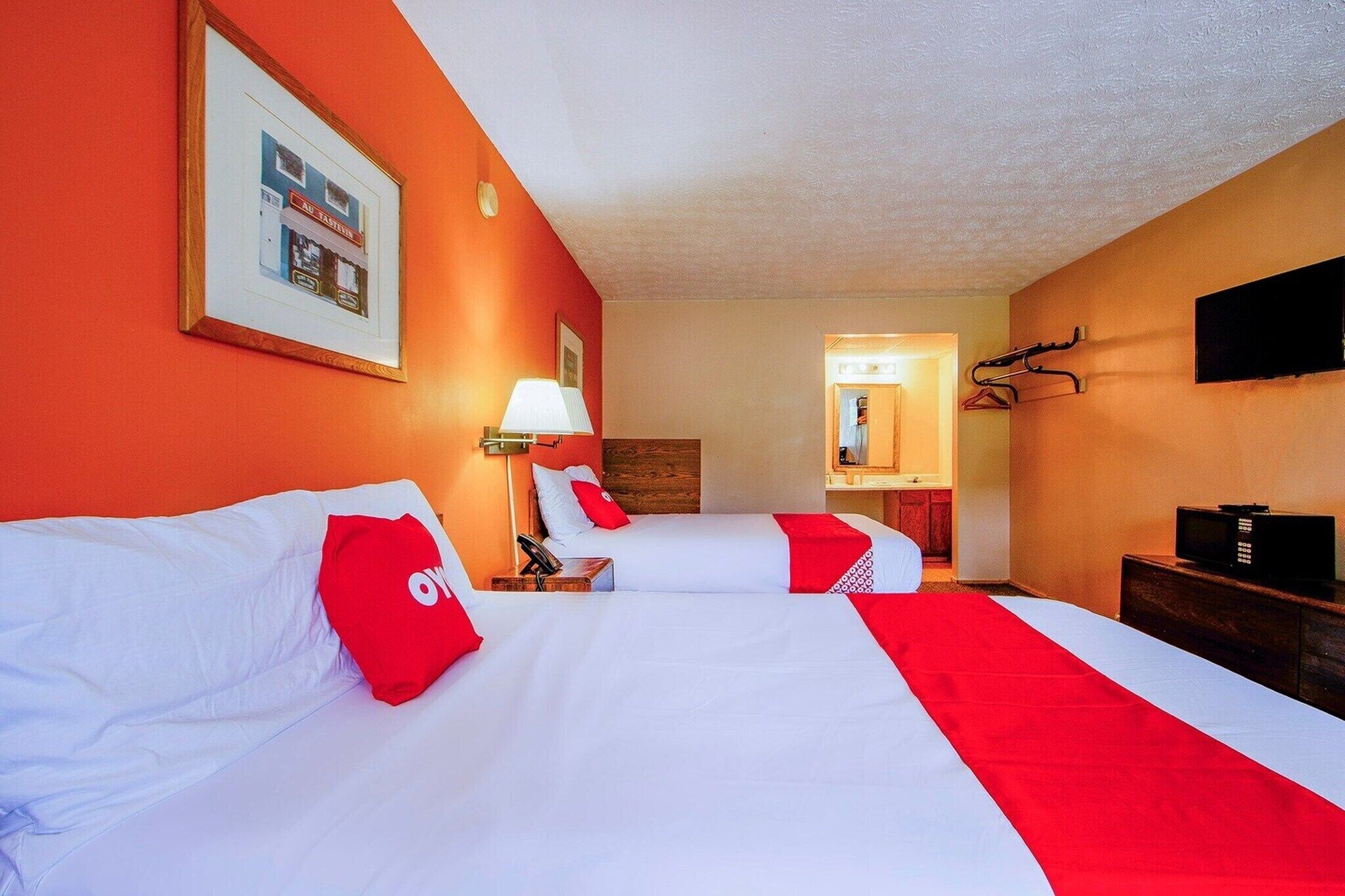 Une chambre d’hôtel avec deux lits, une télévision, une lampe et un porte-manteau.