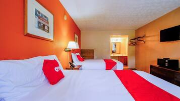 Une chambre d’hôtel avec deux lits, une télévision, une lampe et un porte-manteau.