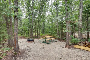 A picnic table in a forested area with trees and a gravel ground.