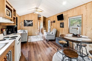 A cabin interior with a kitchen, dining area, and a living room.