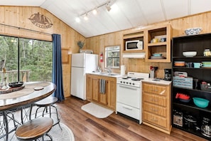 Une cuisine de style rustique, avec des éléments en bois, comprenant un réfrigérateur, une cuisinière, un four à micro-ondes et des placards en bois.