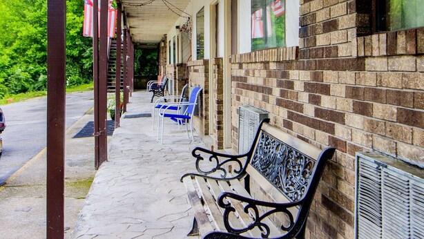 A covered porch with benches, American flags, and a brick building.