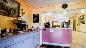 A reception area with a coffee machine, a counter, and a clock on the wall.