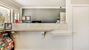 A reception desk with a marble top, framed pictures on the wall, and a wooden bookshelf with brochures.