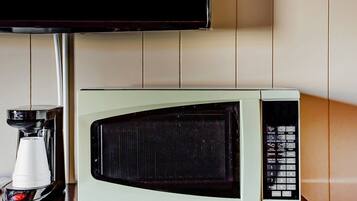 A microwave oven with a digital display and control panel, a coffee maker, and a television mounted on the wall.