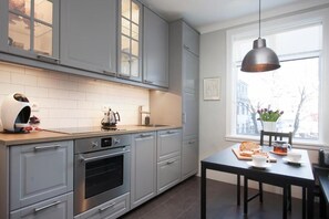 Eine moderne Küche mit grauen Schränken, einem eingebauten Backofen und einem Essbereich mit Tisch und Stühlen.