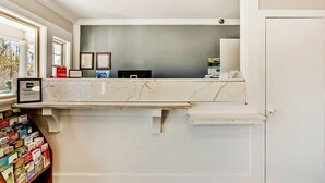 A reception desk with a marble top, framed pictures on the wall, and a bookshelf with magazines.