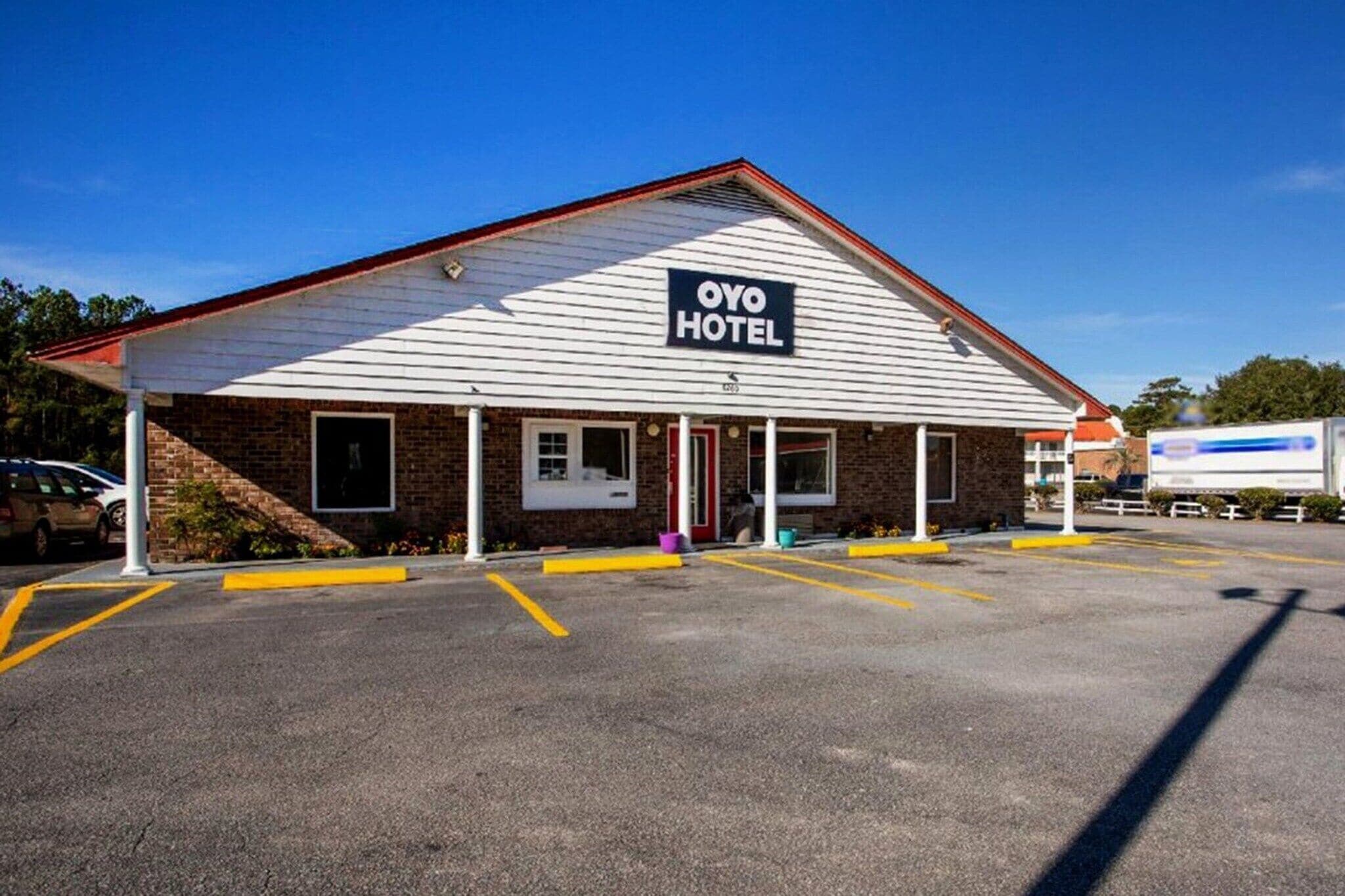 A single-story building with a flat roof, a sign reading 'OYO HOTEL,' and a parking lot with marked spaces.