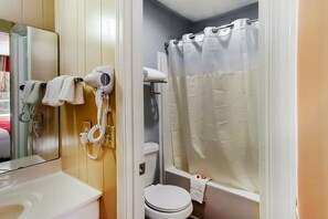Un baño con inodoro, cortina de ducha, secador de pelo y toallero.