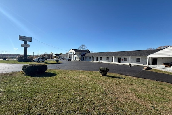 A motel with a signboard, a parking lot, and a building with a flat roof.