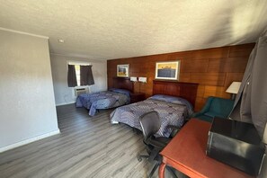 A hotel room with two beds, a desk, a chair, a lamp, a window, and a wooden wall panel. - 2 Full Bed|Smoking|Danville VA (Danville VA)