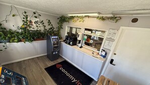 Una habitación con una recepción, un cajero automático, una puerta con lector de tarjetas y un felpudo.