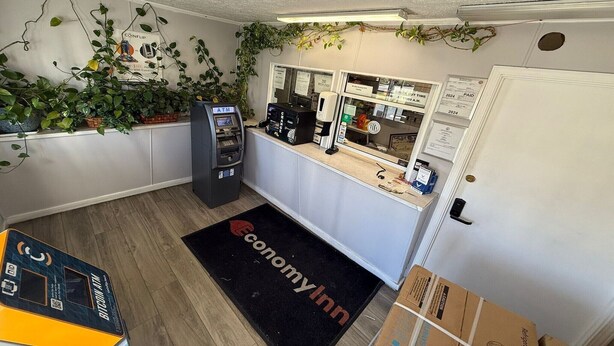 Un espace d’accueil comprenant un distributeur automatique de billets, une machine à café, un tableau d’affichage et une porte dotée d’un clavier pour l’ouverture à code.