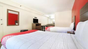 A hotel room with two beds, a TV, a desk, and a mirror.