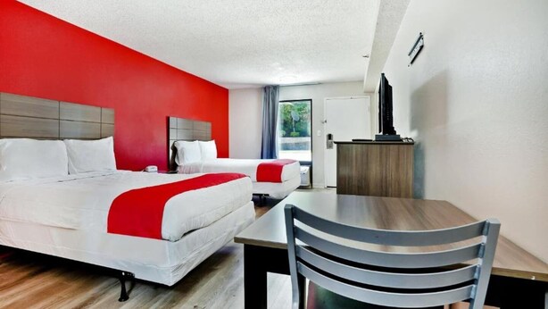 Une chambre d’hôtel avec deux lits, une table à manger et une chaise.