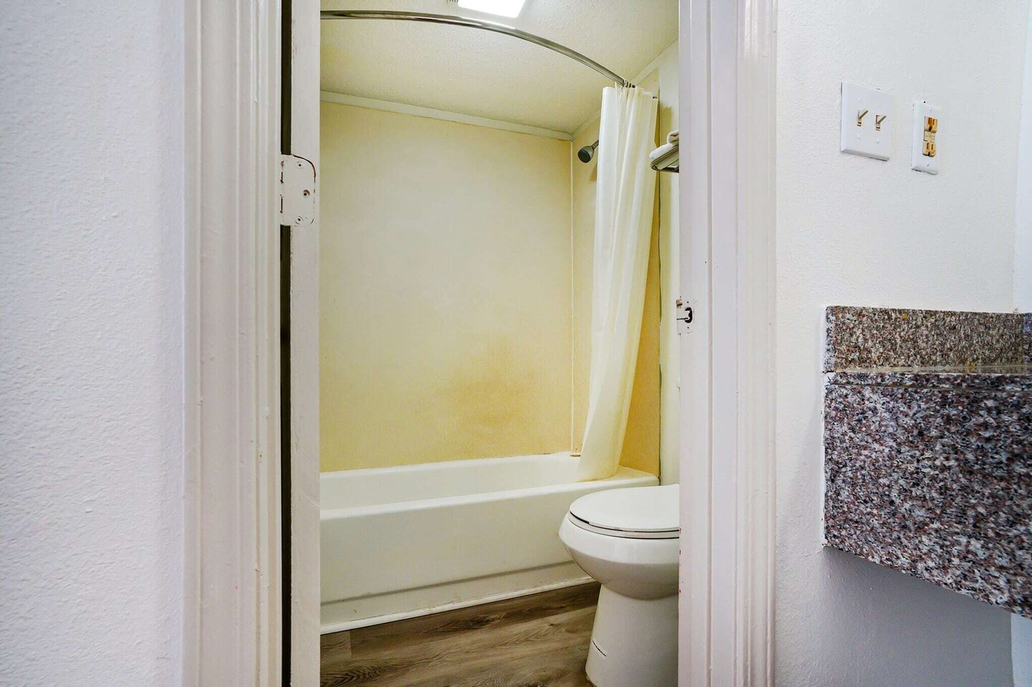 A bathroom with a bathtub, toilet, and a shower curtain.