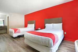 Ein Hotelzimmer mit zwei Betten, einer roten Akzentwand und Holzboden.