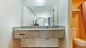 Ein Badezimmer mit Marmorwaschtisch, Spiegel, Toilette und Duschvorhang.