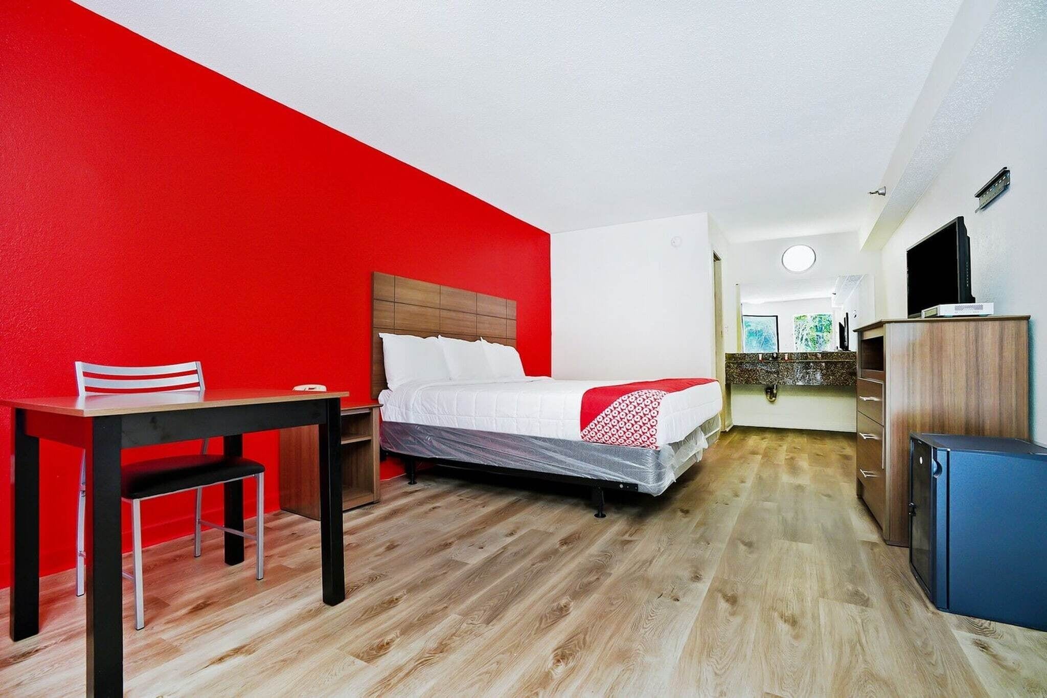 Une chambre d’hôtel comprenant un lit, un bureau, une chaise, une armoire et un téléviseur.